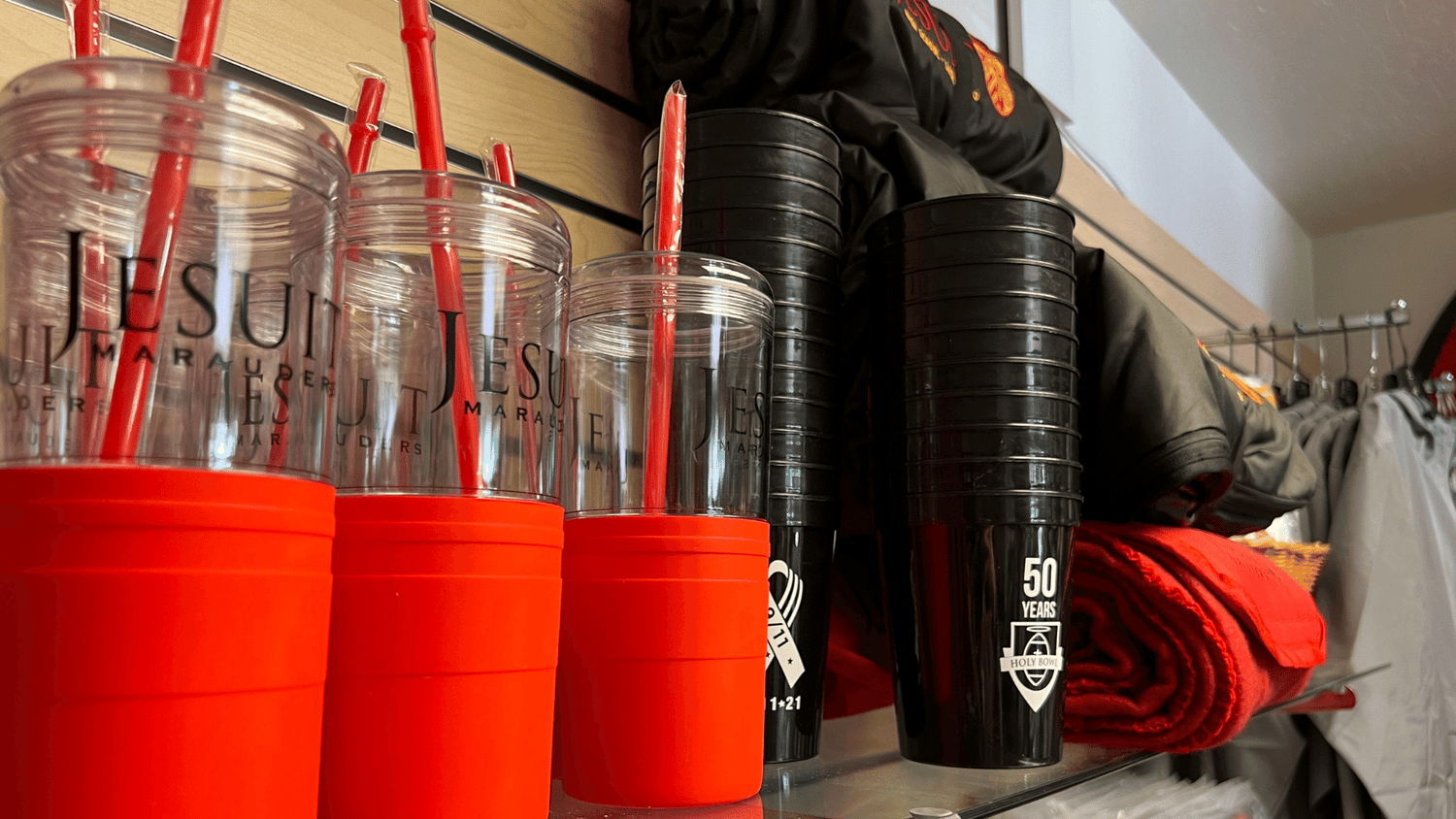 shelf full of reusable tumblers with straws, commemorative plastic cups